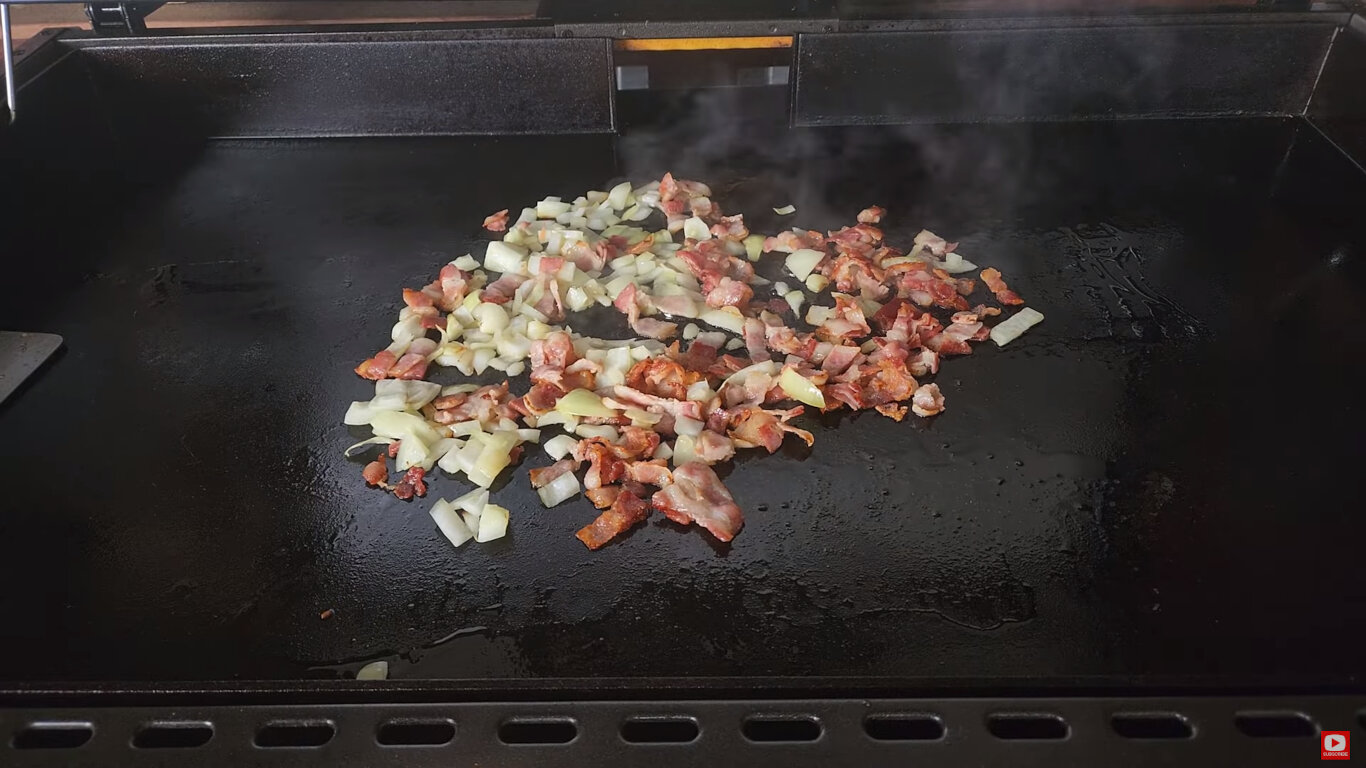 Bacon and onion frying on a griddle 